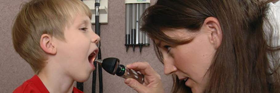 Female clinician looks inside the mouth of a young boy